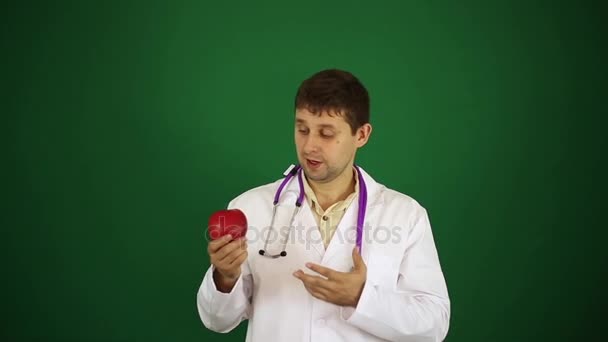 Doutor com maçã em um fundo verde . — Vídeo de Stock