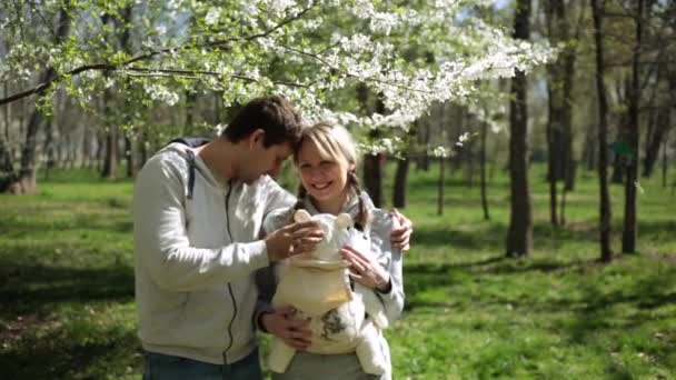 Familia feliz con el bebé en el parque. Pareja joven con bebé sobre fondo natural . — Vídeos de Stock