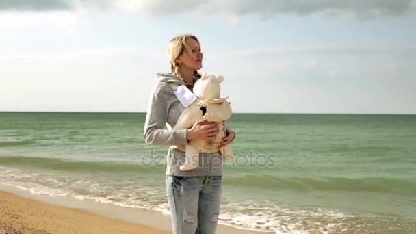 Madre con bebé en la playa. Mujer con bebé en honda en la naturaleza. Mamá con un bebé en un cabestrillo. Una mujer con un hijo junto al mar . — Vídeo de stock