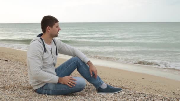 Un homme réfléchit sur la plage. Un homme pense sur la plage. Souvenirs, réflexions, solitude . — Video