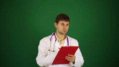 Yeşil bir arka plan üzerine doktor. Doktor tablet üzerinde yazar. Erkek bir doktor bir not defterinde yazıyor.