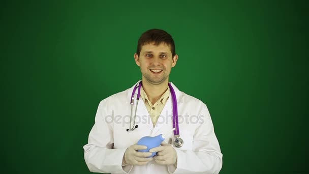 Docteur avec un lavement dans les mains. Le docteur tient un lavement. Un médecin masculin sur fond vert . — Video