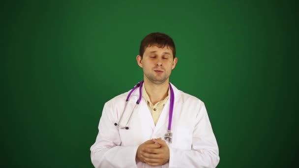 Doctor says to the camera. A male doctor is talking. Doctor on a green background. — Stock Video