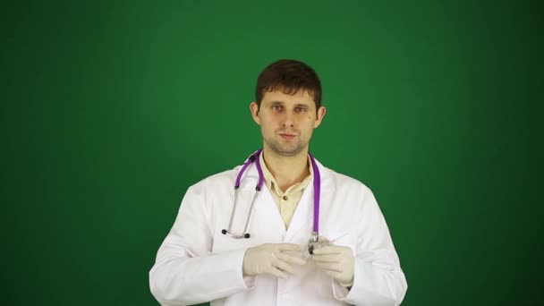 Doktor na zeleném pozadí pomocí injekční stříkačky. Doktor proti injekce. — Stock video