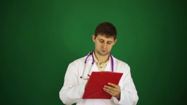 Doktor yeşil bir arka plan üzerine bir not defterinde yazıyor. Doktor tıbbi geçmişini yazıyor.