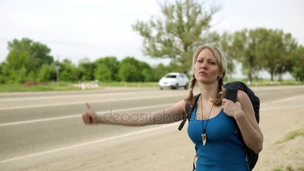 Το κορίτσι σταματάει το αυτοκίνητο στο δρόμο. Νεαρή γυναίκα να κάνει ωτοστόπ κατά μήκος ενός δρόμου. — Αρχείο Βίντεο