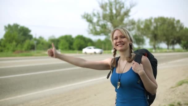 Vrolijk meisje liften op de weg. Reizen, wandelen, liften. — Stockvideo