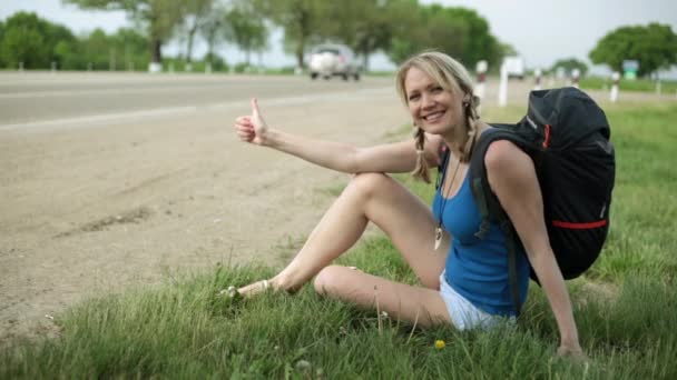 Cheerful girl hitchhiking on the road. Travel, hiking, hitchhiking. — Stock Video