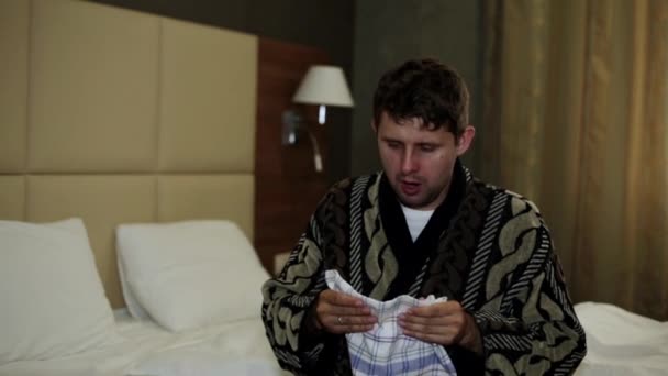 El hombre frío estornuda en su pañuelo. El hombre estornuda en el dormitorio . — Vídeos de Stock
