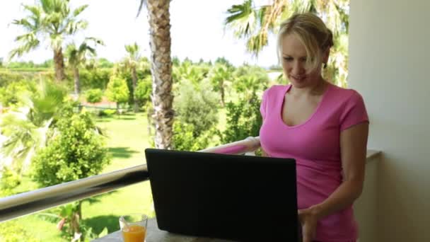 Mulher com laptop em um fundo de palmeiras. Menina com laptop na varanda do hotel . — Vídeo de Stock