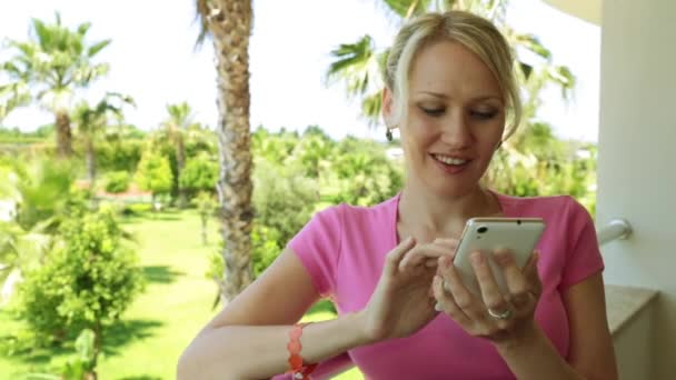 Palmiye ağaçları bir arka plan üzerinde bir akıllı telefon olan kadın. Kız bir smartphone otel balkonda kullanır.. — Stok video