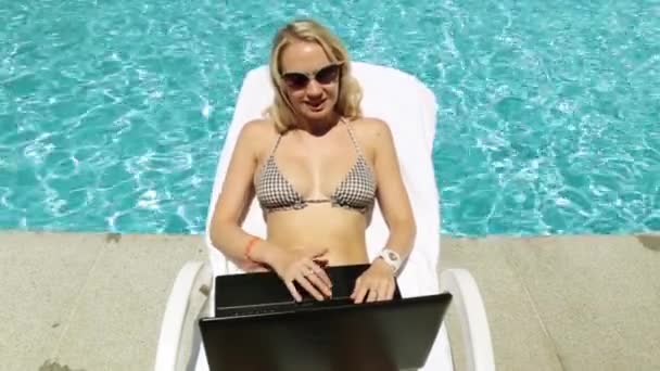 Donna con computer portatile sullo sfondo della piscina. Ragazza con computer portatile a bordo piscina . — Video Stock