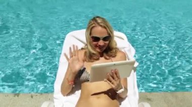 Havuzu görüşmeler Skype bir kadın. Kız bir tablet kullanarak video iletişimi iletişim kurar..