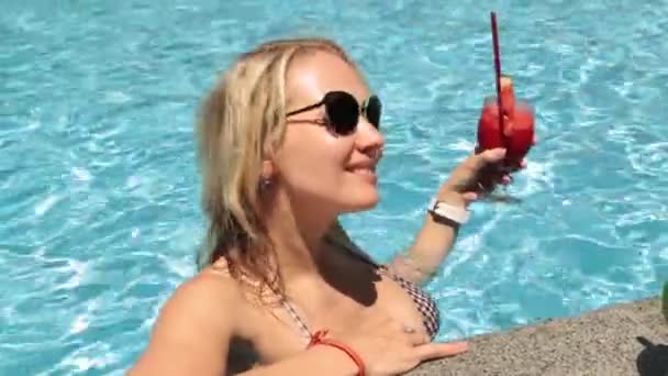 Een vrouw is een cocktail drinken in het zwembad. Meisje in een zwempak, fruit cocktail, zomer. — Stockvideo