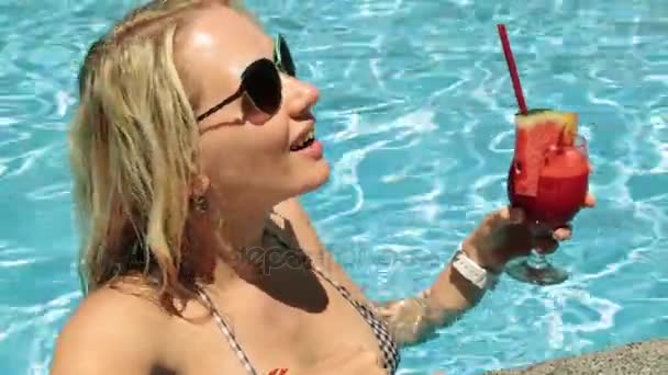 Ragazza con un cocktail di frutta in piscina. Una donna sta bevendo un cocktail in piscina . — Video Stock