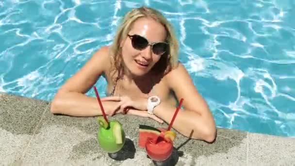 Bella ragazza in costume da bagno con due cocktail. Una donna sta bevendo un cocktail in piscina . — Video Stock