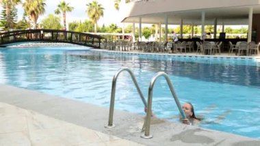 Genç bir kadın havuzda yüzüyor. Güzel bir kız havuzdan geliyor.