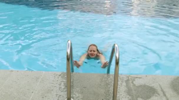 Gyönyörű nő a fürdőruhát a medencénél. Lány a lépcsőn, a medence. Egy fiatal nő kilép a medence. — Stock videók