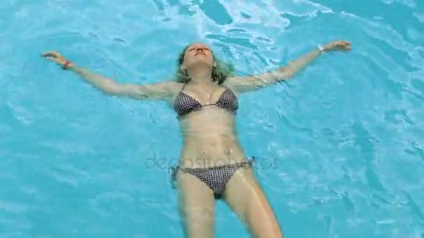 Une jeune femme nage dans la piscine. Belle fille dans une piscine transparente . — Video