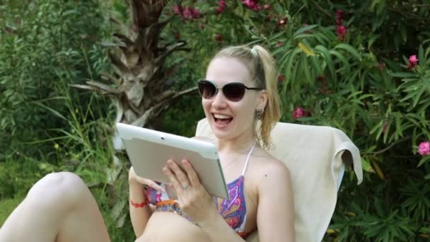 Mooie vrouw in bikini praten over de mededeling van de video. Een meisje in een zwembroek communiceert via skype met behulp van een tablet. — Stockvideo