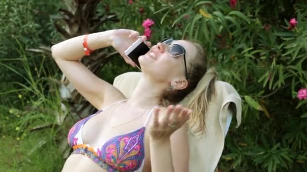 Bella donna in bikini che parla al telefono. Ragazza sulla spiaggia con un telefono. Donna sexy nella natura parla al telefono . — Video Stock