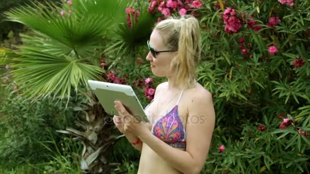 Une fille en maillot de bain communique via skype à l'aide d'une tablette. Belle femme en bikini parlant sur la communication vidéo . — Video