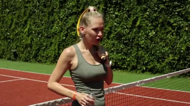 Une jeune femme boit de l'eau après un match de tennis. Joueur de tennis eau potable . — Video