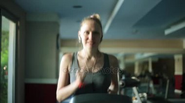 Kız fitness kulübünde çalışıyor. Bir koşu bandı üzerinde çekici kadın.