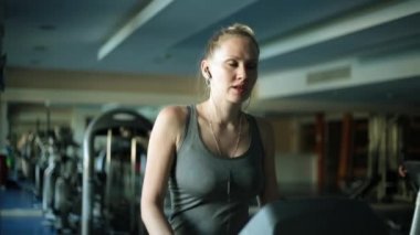 Bir koşu bandı üzerinde çekici bir kadın. Kız koşu bandı yürüyor.