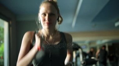 Bir koşu bandı üzerinde çekici bir kadın. Kız fitness kulübünde çalışıyor. Koşu bandı üzerinde atlet.