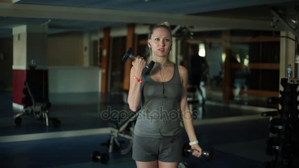 Deportiva con mancuernas. Una joven va a practicar deportes en un gimnasio . — Vídeo de stock