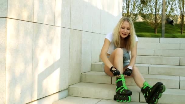 Молода жінка на роликових ковзанах... Блондинка на ролику сидить на сходах . — стокове відео