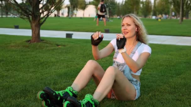 Junge Frau auf Rollschuhen hört Musik im Park. — Stockvideo