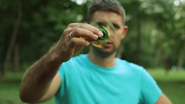 Een man met een populaire speelgoed spinner. — Stockvideo