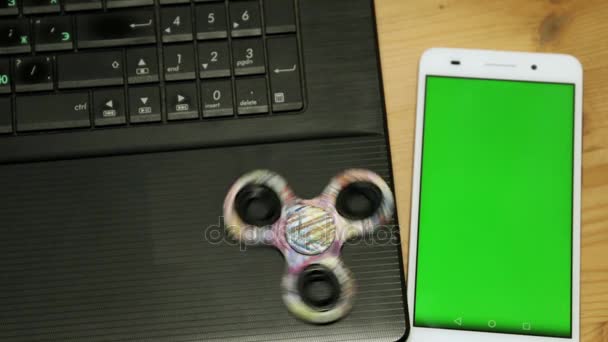 Um spinner de brinquedo e smartphone com uma tela verde. Smartphone e laptop . — Vídeo de Stock