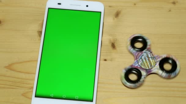 Una donna sta usando uno smartphone con uno schermo verde. Una tavoletta con schermo verde su un tavolo di legno . — Video Stock