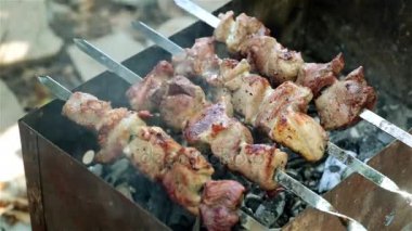 İnsanlar şiş kebap ızgara yemek vardır. Kömürlerin üzerinde kızarmış et.