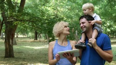 Genç aile ve parkta bir tablet bilgisayar ile küçük çocuk.