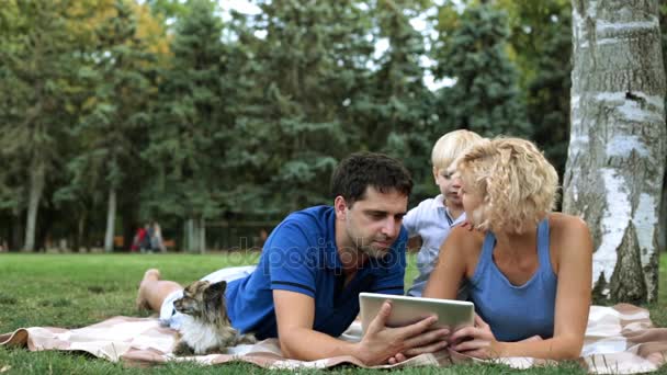 Família com uma criança e um tablet no parque. Família feliz e tecnologia digital . — Vídeo de Stock