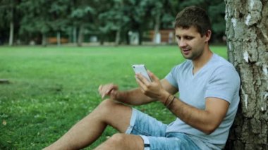 Parkta bir akıllı telefon olan bir adam. Internet'te doğada bir akıllı telefon kullanan bir adam.