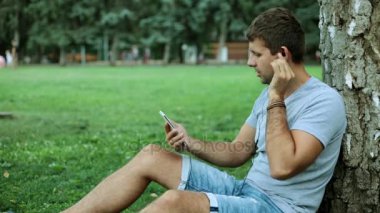 Bir adam parkta bir smartphone kullanarak güçlü rock müziği dinliyor.