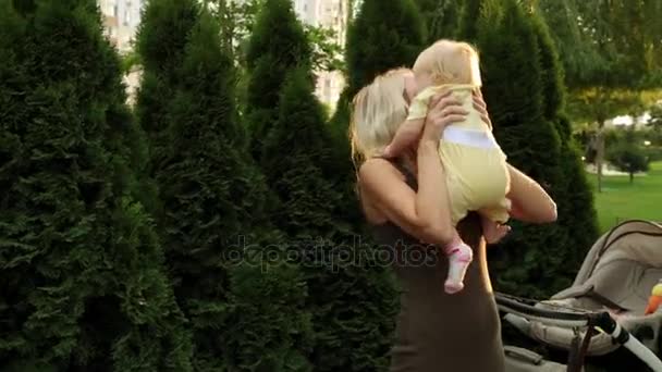 Eine junge Frau hält ein kleines Kind in der Hand. Mutter mit Baby im Park. — Stockvideo