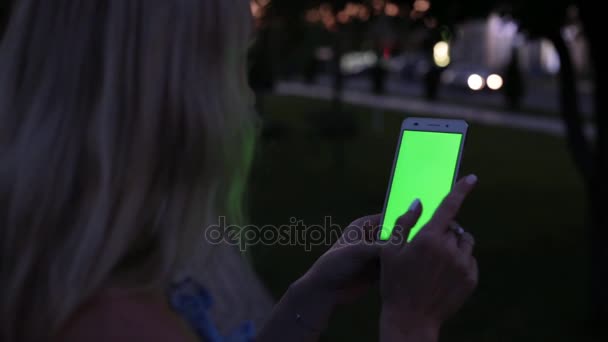 Una persona utiliza un teléfono inteligente con una pantalla verde. Una mujer sostiene un teléfono inteligente con una pantalla verde . — Vídeo de stock