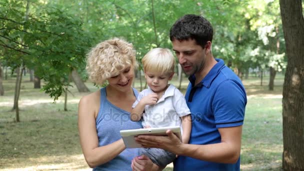 Een gezin met een kind is het bezit van een tablet-pc. Moeder, vader en zoon met een tablet. — Stockvideo