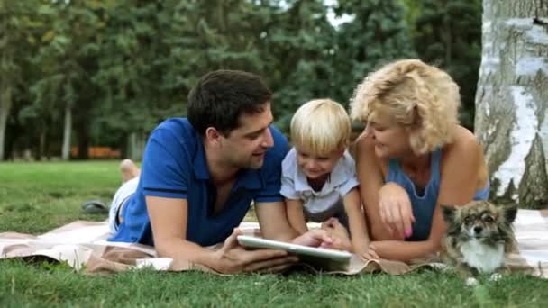 Jong (echt) paar met een kind genieten van een tablet-pc. — Stockvideo