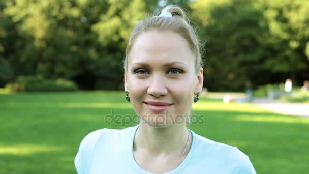 Jovem mulher bonita está sorrindo no fundo da natureza. Retrato de uma menina atraente . — Vídeo de Stock
