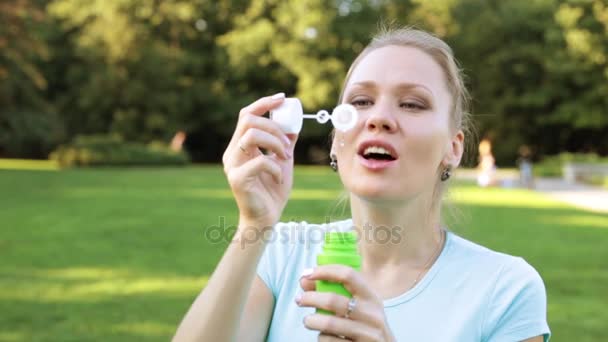 Joven mujer soplando burbujas de jabón en el parque. — Vídeos de Stock