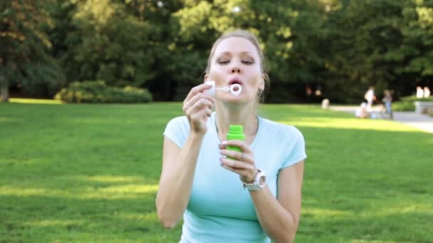 Een vrouw blaast bellen. Meisje blazen van zeepbellen in het park. — Stockvideo