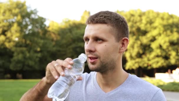 Un hombre blanco bebe agua de una botella . — Vídeos de Stock
