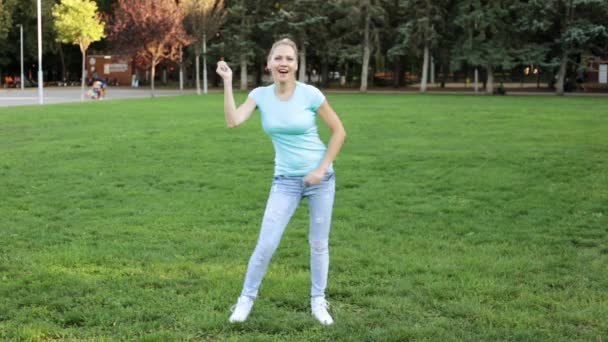 Uma jovem mulher está se divertindo dançando no parque . — Vídeo de Stock